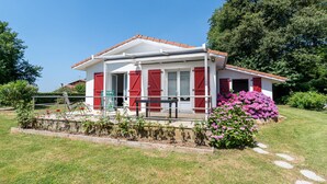 A single-story house with a white facade, red shutters, and a tiled roof.