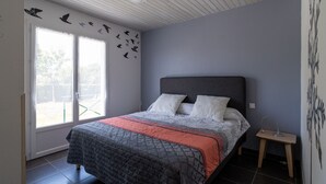 A bedroom with a bed, a nightstand, a window with blinds, and a wall with bird decals.