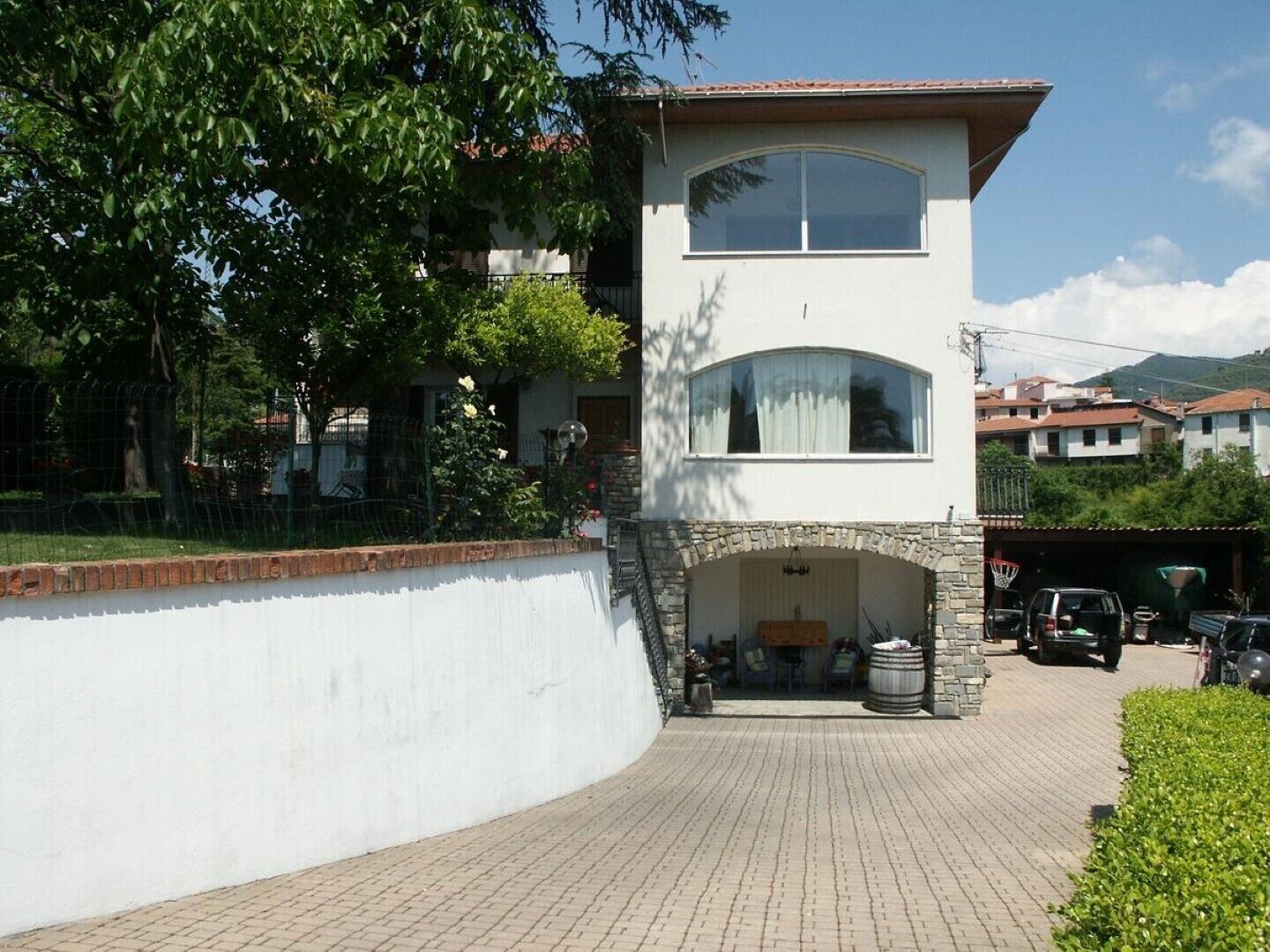 A two-story building with a stone archway entrance, a basketball hoop, and a car parked outside.