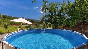 Ein Pool mit einer Leiter, umgeben von Grünpflanzen und einem Holzzaun.