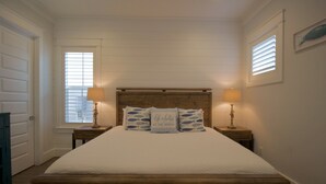 Un dormitorio con una cama de madera, dos mesitas de noche con lámparas y una ventana con persianas.