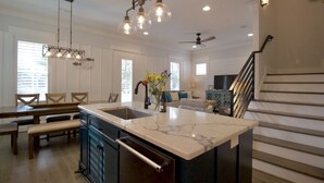 Una cocina amplia con una isla grande, mesa de comedor de madera y bancos.