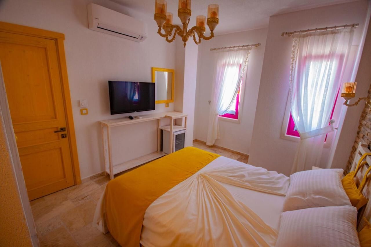 A hotel room with a bed, a TV, a desk, and a window with curtains.