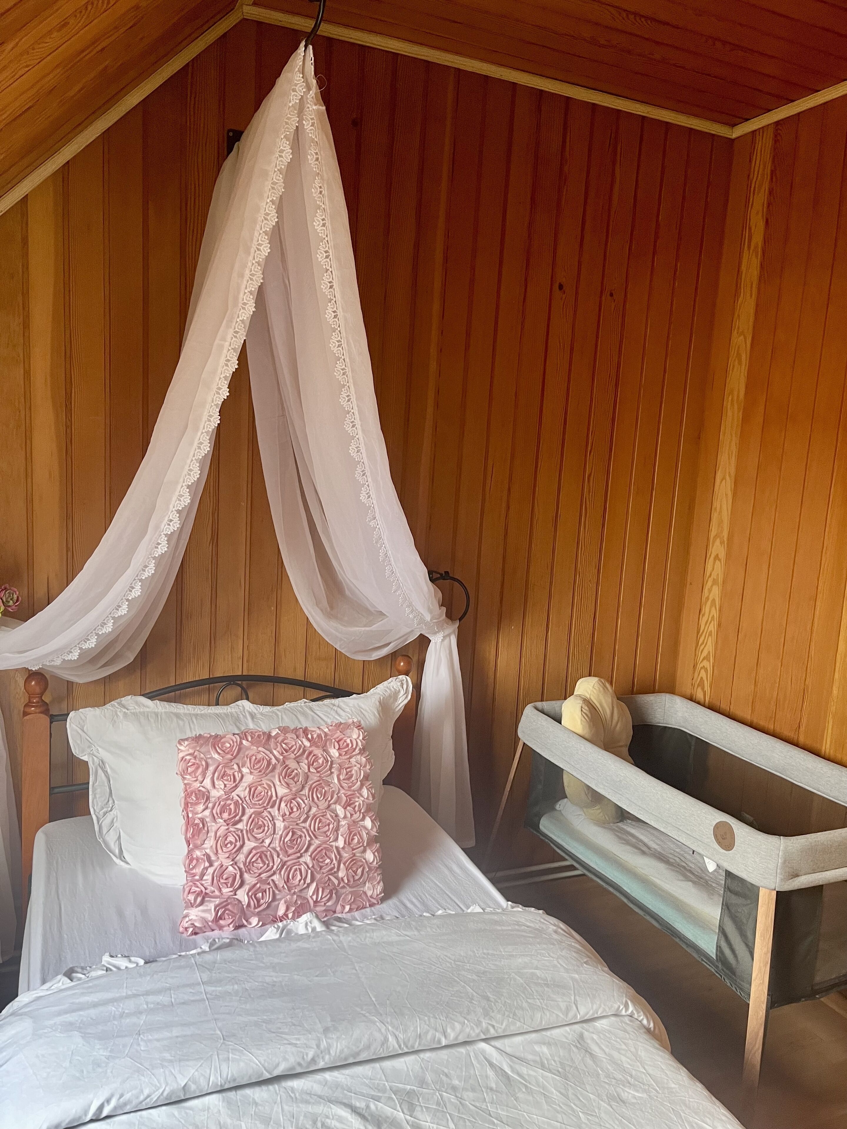 Un dormitorio con cama a dosel, una mesita de noche pequeña y un banco.