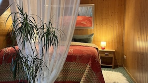 Una camera da letto con un letto, un comodino, una lampada, una pianta in vaso e un baldacchino.