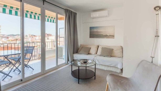 A modern living room with a sofa, a glass coffee table, and a chair. There is a balcony with a view of the city. - Central apartment with balcony by Costarentals - Ref 92 (Costa del Sol)