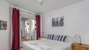 Een hotelkamer met een bed, een nachtkastje, een schilderij en uitzicht op het buitenbalkon.