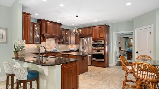 A modern kitchen with wooden cabinets, stainless steel appliances, and a central island with bar stools.