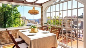 Un coin repas avec une table dressée pour quatre personnes, de grandes fenêtres et une vue sur le paysage urbain.