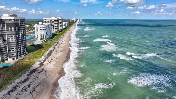 Ein Küstenhotel mit mehreren Hochhäusern, einem Sandstrand und Blick aufs Meer.