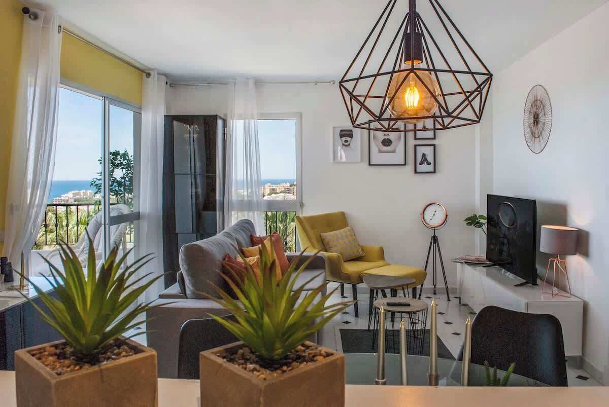 A modern living room with a sofa, chairs, a dining table, and a large window with a view.