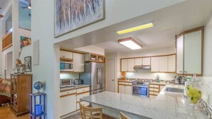 Una cocina moderna con una isla grande, electrodomésticos de acero inoxidable y armarios de madera.
