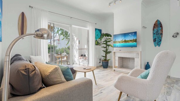 Un salon spacieux comprenant un canapé, un fauteuil et un coin repas avec une table et des chaises.