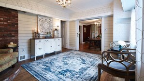 Una habitación con pared de ladrillo blanco, una araña, un armario blanco y un tapete con estampado azul.