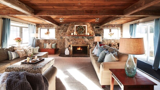Una sala de estar acogedora con chimenea de piedra, vigas de madera en el techo y asientos cómodos.