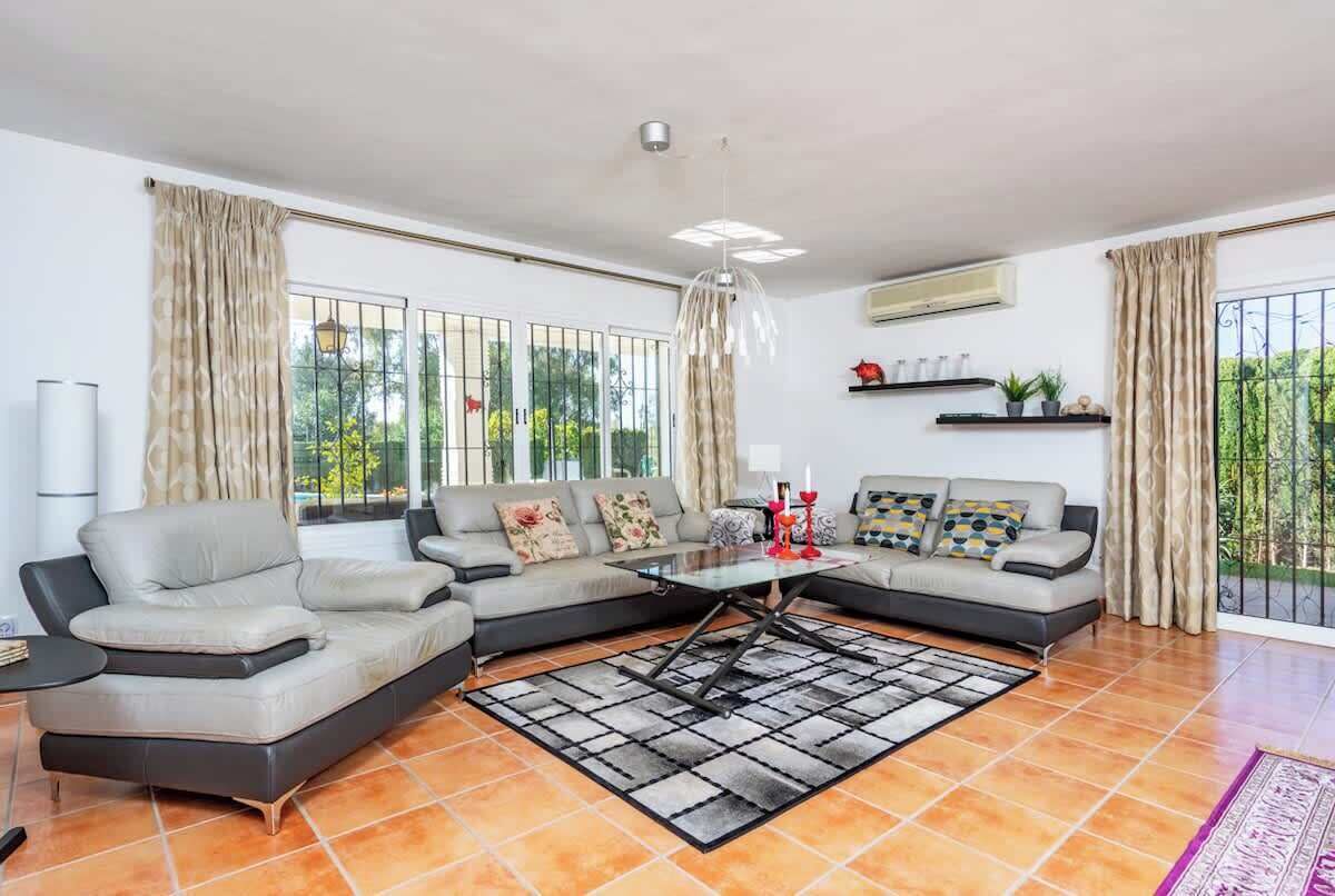 Ein modernes Wohnzimmer mit einem Ecksofa, einem Couchtisch und einem großen Fenster mit Vorhängen.