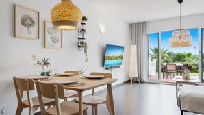 A modern dining area with a large table, chairs, and a television on the wall. - Charming seaview apt by Costarentals - Ref 49 (Las Lagunas de Mijas)