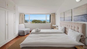 A hotel room with a large bed, a sofa, a window with a view of the sea, and a wardrobe. - Charming seaview apt by Costarentals - Ref 49 (Las Lagunas de Mijas)