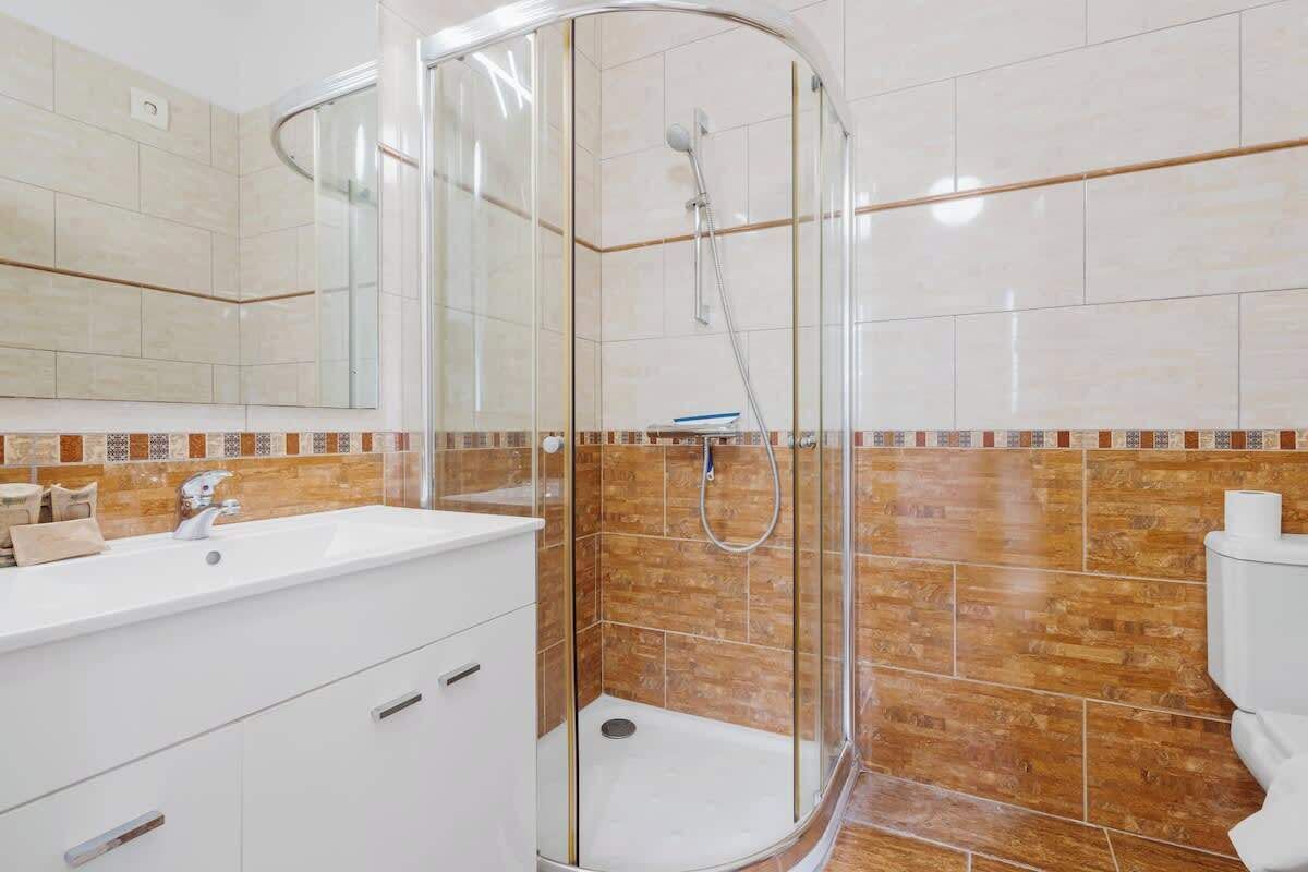 A modern bathroom with a glass-enclosed shower, a white sink, and a tiled backsplash.