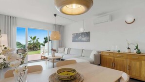 A modern living room with a dining area, large windows, and a view of the outdoors. - Charming seaview apt by Costarentals - Ref 49 (Las Lagunas de Mijas)