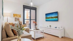 Ett modernt vardagsrum med en soffa, ett soffbord och ett vitt konsolbord med en platt-TV.