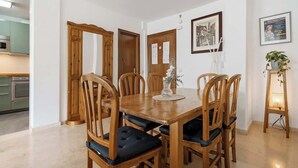 Un comedor con una mesa y sillas de madera, un jarrón con flores y cuadros en la pared.