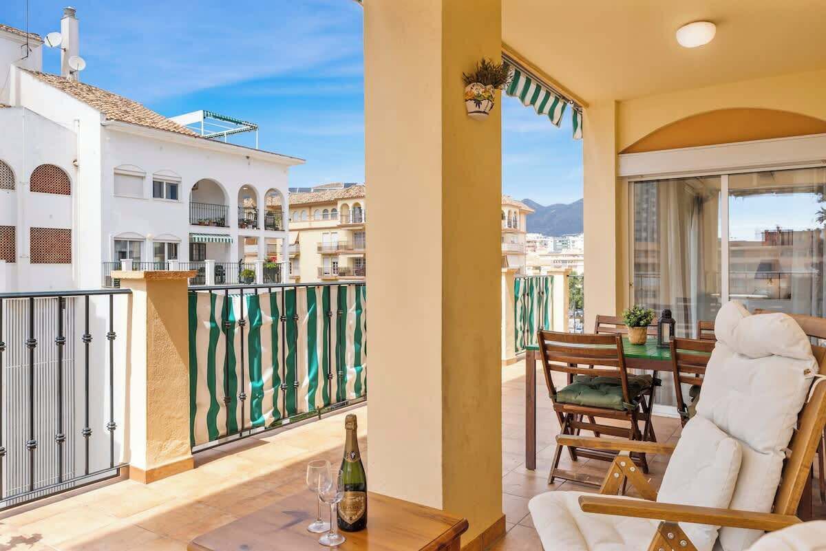 A balcony with a table, chairs, and a bottle of champagne.