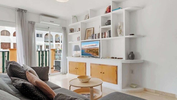 Una sala de estar moderna con un sofá, televisión y estantería.