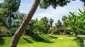 Un campo de golf bien cuidado con un camino despejado, rodeado de vegetación exuberante y palmeras.