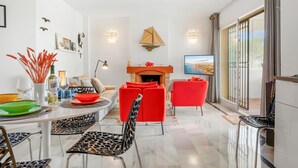 Una sala de estar moderna con chimenea, sillas rojas, una mesa de comedor con sillas y un ventanal con vistas.