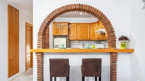 Una cocina con un arco de ladrillo, armarios de madera y dos sillas.