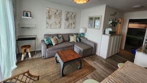 A compact living space with a sofa, coffee table, and a kitchenette. - Beach view condo with private deck (Ocean City)