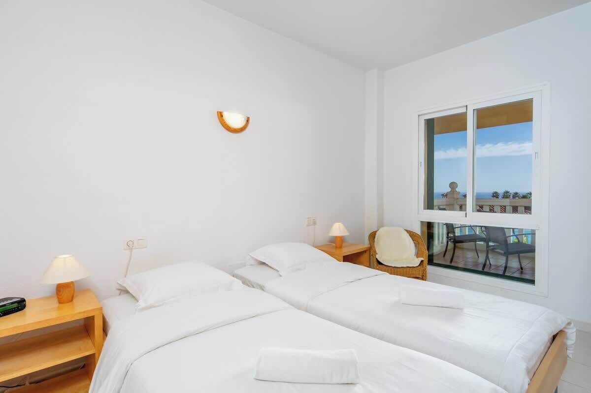 Een hotelkamer met twee bedden, een raam met uitzicht, een stoel en een lamp.