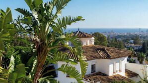 A white building with a tiled roof, surrounded by lush green foliage. - Urb Villa with pool by Costarentals- Ref 139 (Mijas)