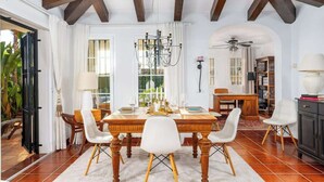 A dining room with a wooden table, white chairs, and a chandelier. - Urb Villa with pool by Costarentals- Ref 139 (Mijas)