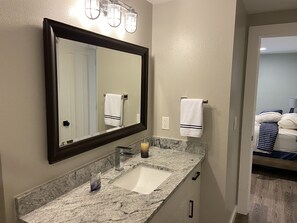 A bathroom with a marble sink, a large mirror, and two towels hanging on the wall.