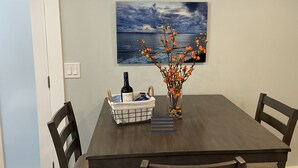 Een eettafel met stoelen, een fles, een mand en een vaas met bloemen.