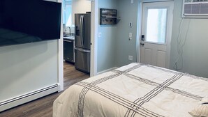 Een slaapkamer met een bed, een plafondventilator, een deur en een raam.