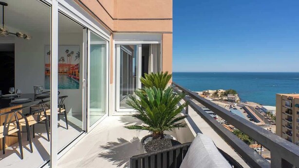 Een balkon met een eethoek, een potplant en uitzicht op zee.
