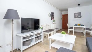 A modern living room with a flat-screen TV, white furniture, and a dining area with a table and chairs. - Central Gem Los Boliches by Costarentals - Ref 77 (Costa del Sol)