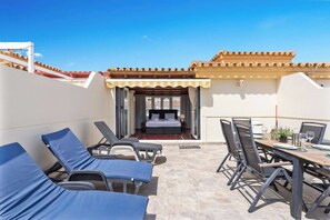 A hotel room with a bed, a balcony, and a dining area with chairs and a table.