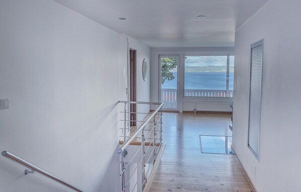 Un pasillo con piso de madera que conduce a un balcón con vista al mar.