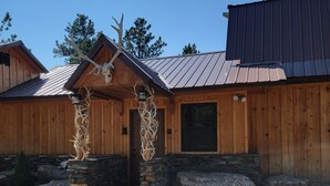A wooden cabin with a stone foundation, a metal roof, and antlers displayed outside. - Remote peaceful cabin,  great wildlife viewing, hunting and fishing close by (Wheatland)