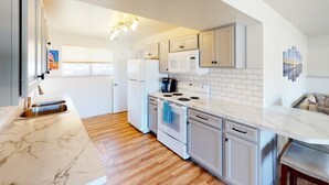 Una cocina moderna con armarios blancos, una encimera de mármol y un horno empotrado.