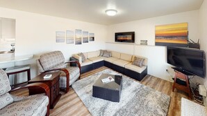 Una sala de estar moderna con un sofá modular, un televisor y obras de arte en las paredes.