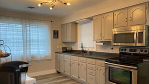 A modern kitchen with stainless steel appliances, light wood cabinetry, and a central island. - In the Heart of Three Oaks - Steps to Downtown (Three Oaks)