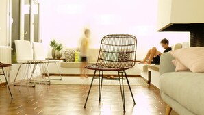 Una sala de estar moderna con una silla de mimbre, un sofá y una mesita de centro.