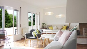 Una sala de estar con sofá, sillón y una mesita. Hay dos puertas que dan a un balcón.