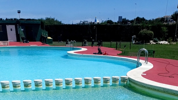 Een zwembad met helder water, omgeven door een terrasgedeelte in rood en wit.