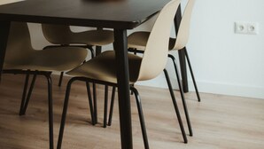 Un espace repas avec une table en bois foncé, des chaises de couleur beige et des lampes suspendues.